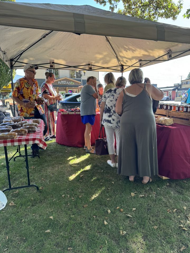 Shoppers browsing under a market tent at Pioneer Park